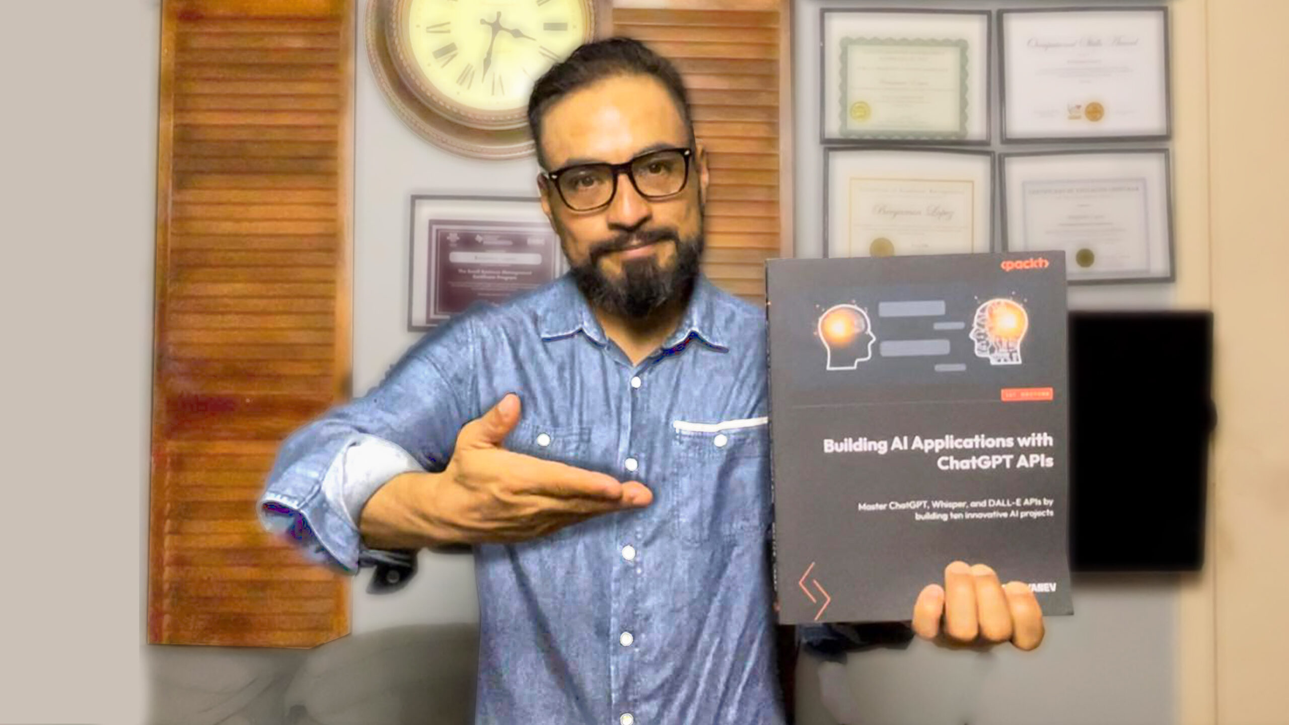 Person holding the book 'Building AI Applications with ChatGPT APIs' while gesturing towards it.